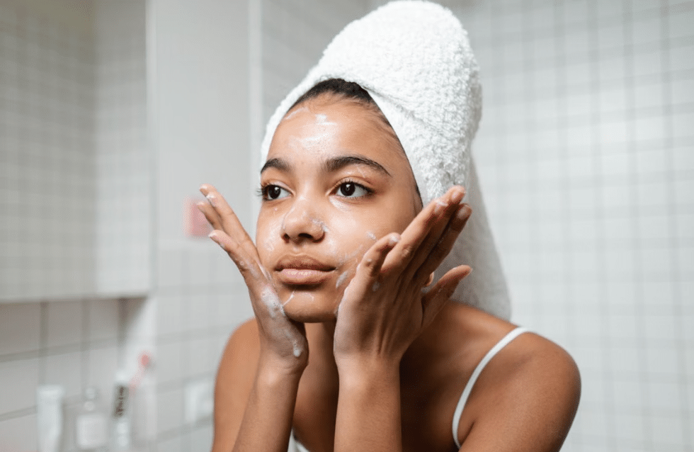 Femme nettoyant son visage dans le cadre d'une routine anti-taches quotidienne